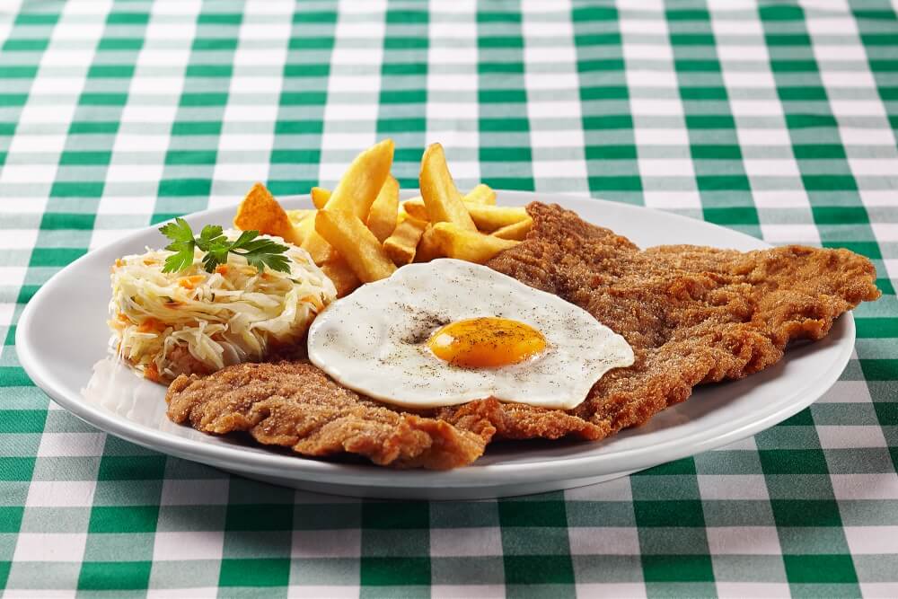 photography of schnitzel served with egg and fries shot for the card of an restaurant
