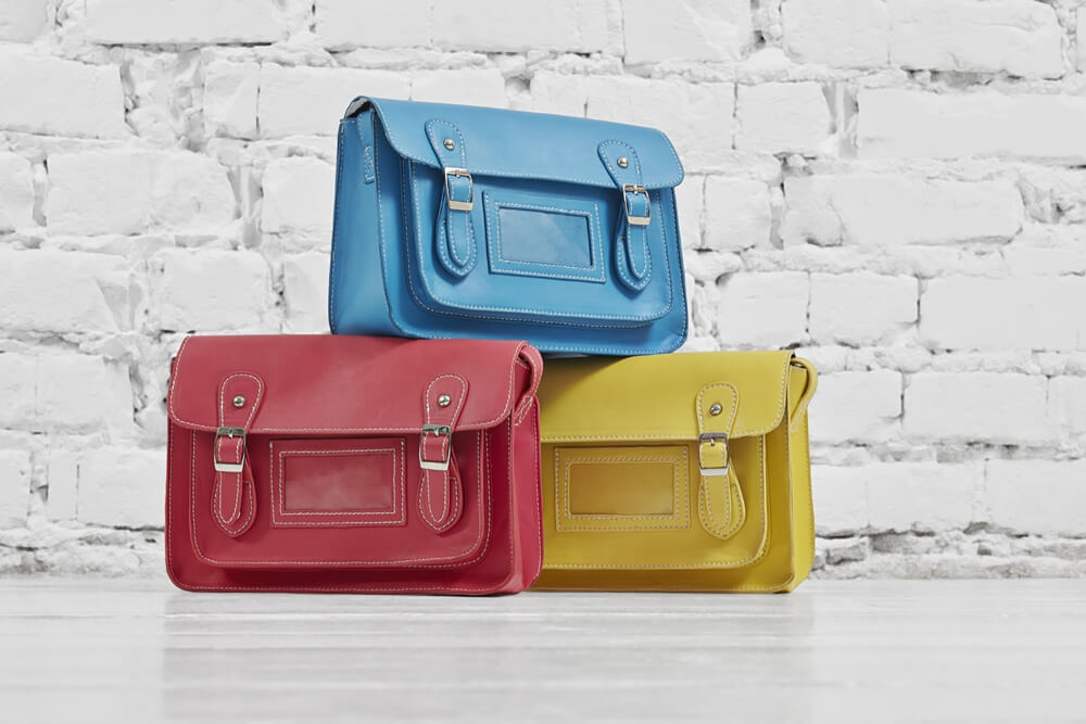 commercial photo of three color variations of the same handbag model on a bright background