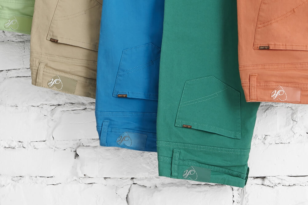 a photo of House brand trousers in differnt colours with an white brick wall in the background 