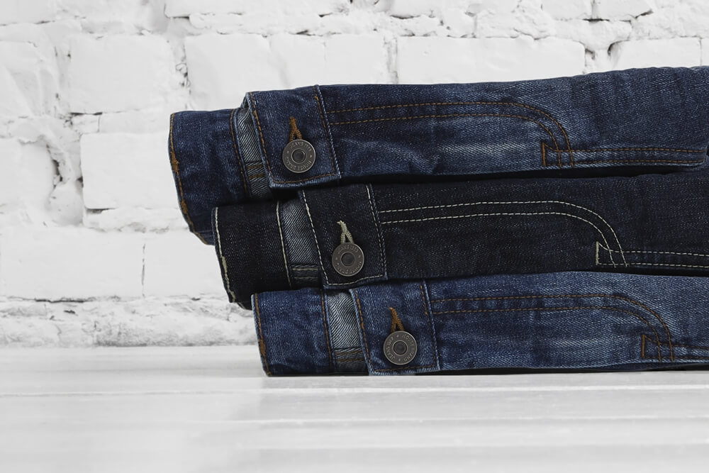 detail shot of three pairs of House jeans in various colors
