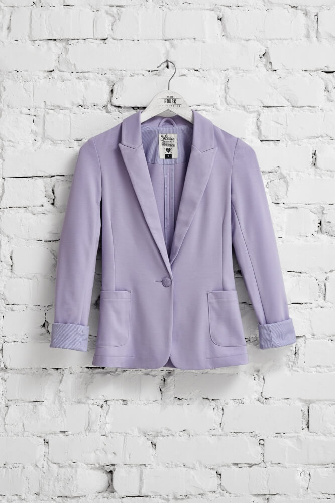 a photo of a coat hanging on a white brick wall