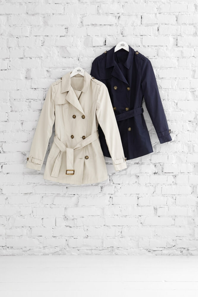 a photo of two color variations of a House brand coat hanged in arrangement on a bright brick wall