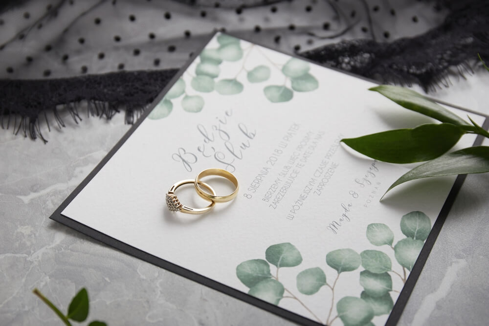 still life photo of wedding stationery placed next to a pair of wedding rings 