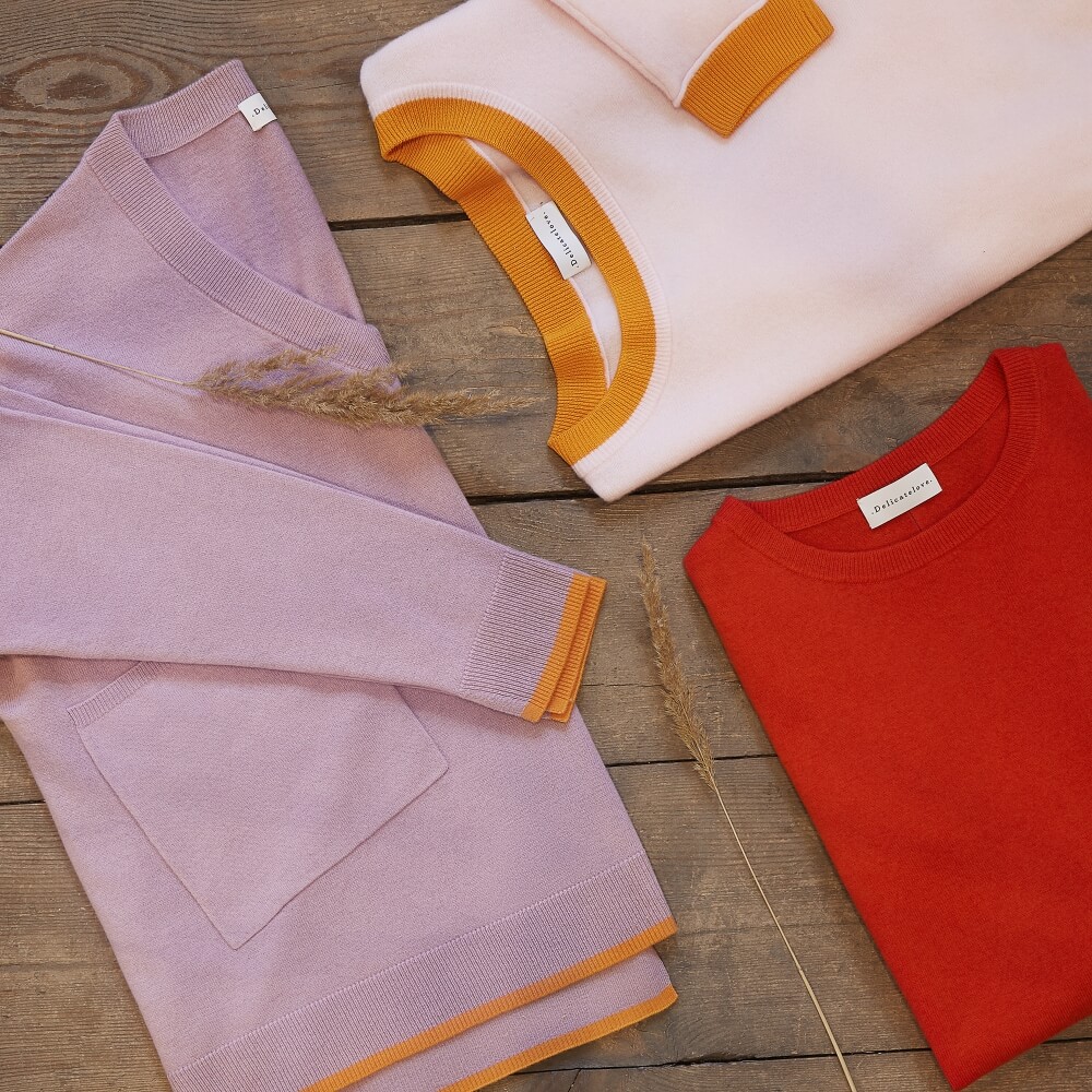 zdjęcie flat lay trzech modeli bluz Delicatelove ułożonych na jasnych deskach