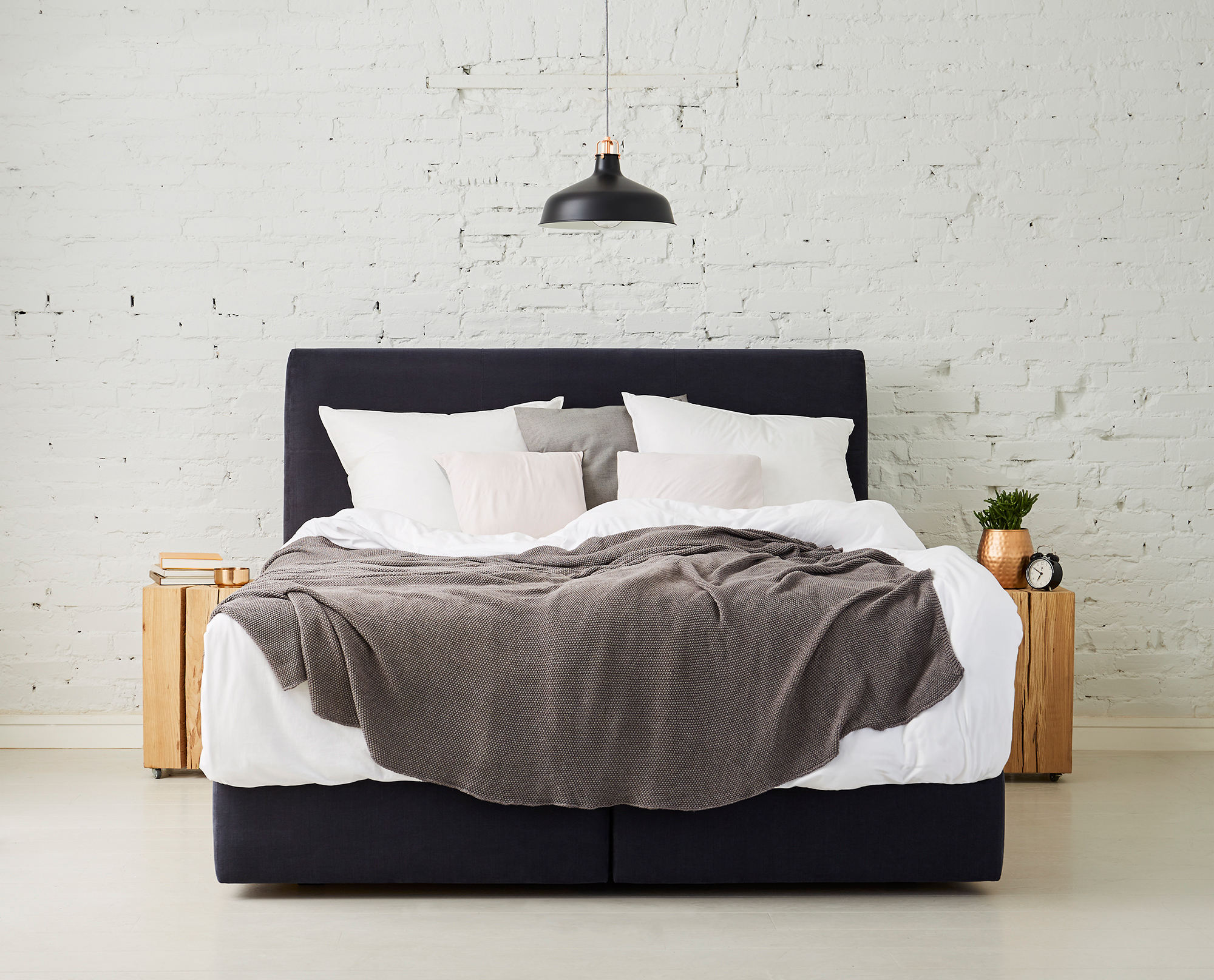front photo of a bed in a room with bright brick wall stylized with daylight light