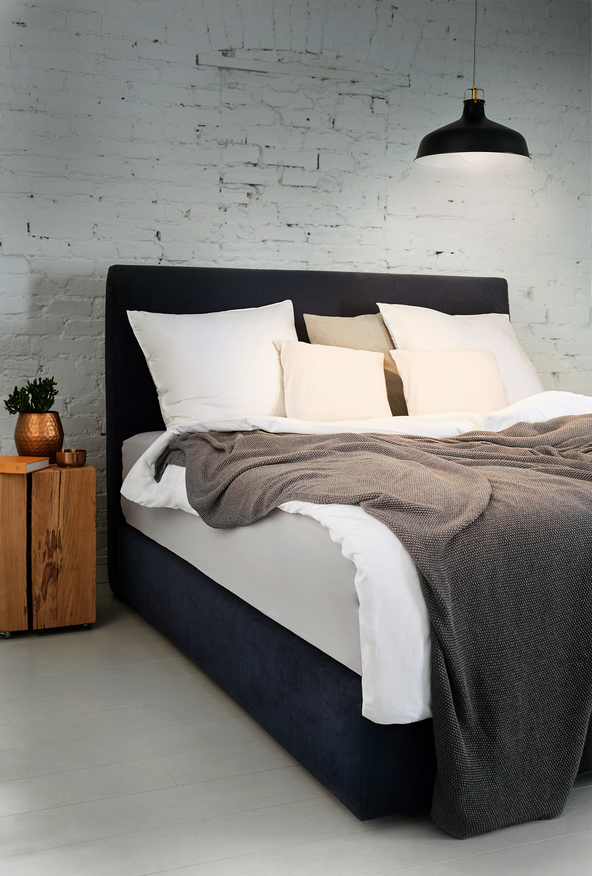 angle shot of a bed in a bright room stylized with light source from a lamp above