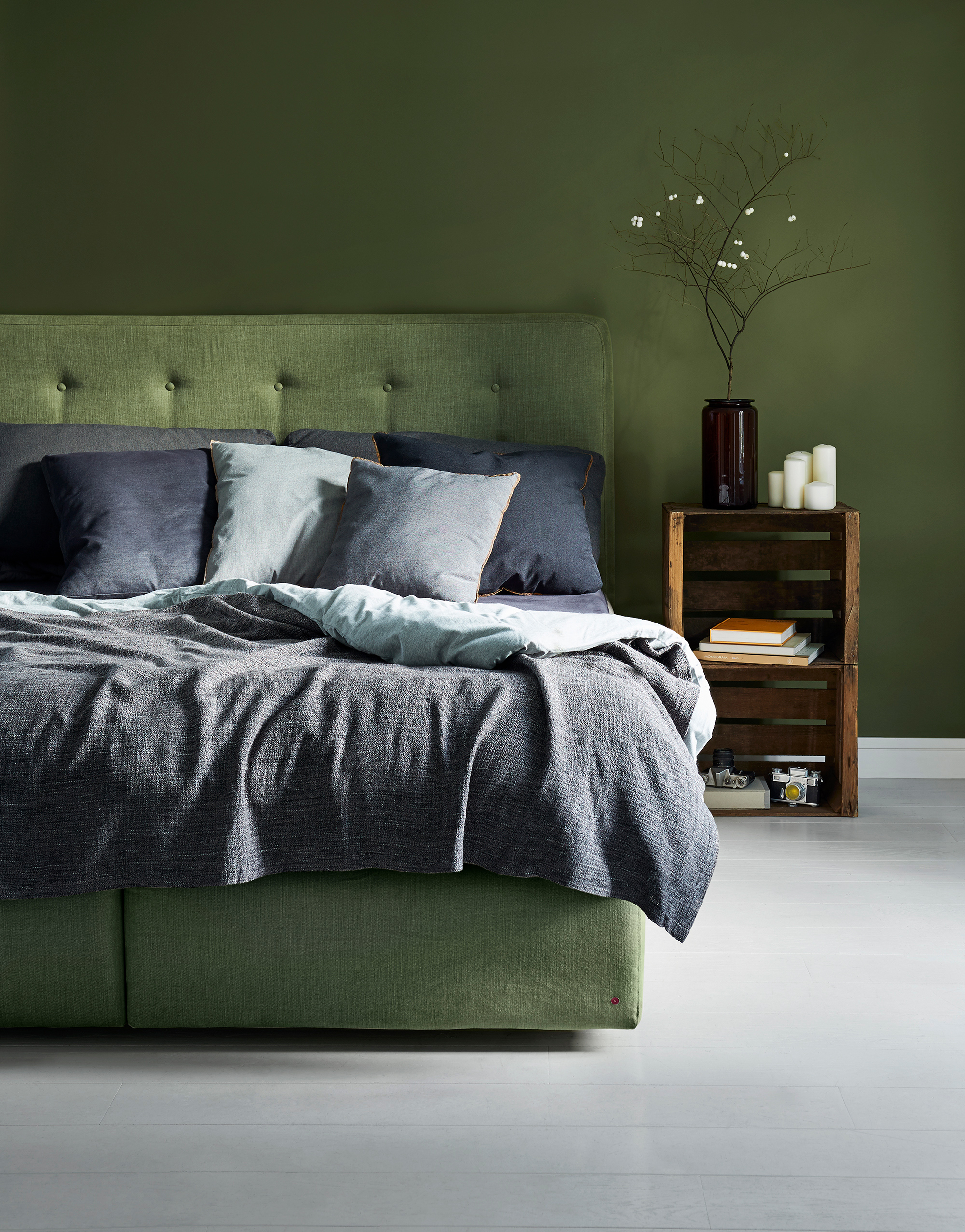 a photo of an green bed in a room with grey floor and green walls with lights set to imitate daylight inside