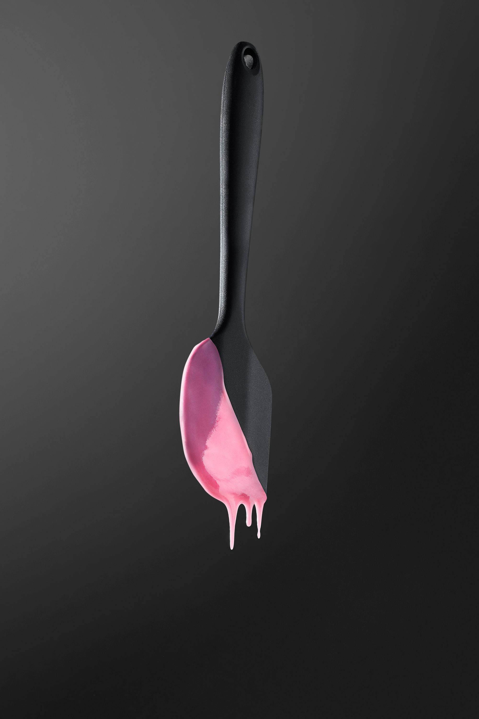 photo of a kitchen spatula in the air with dripping pink sauce 