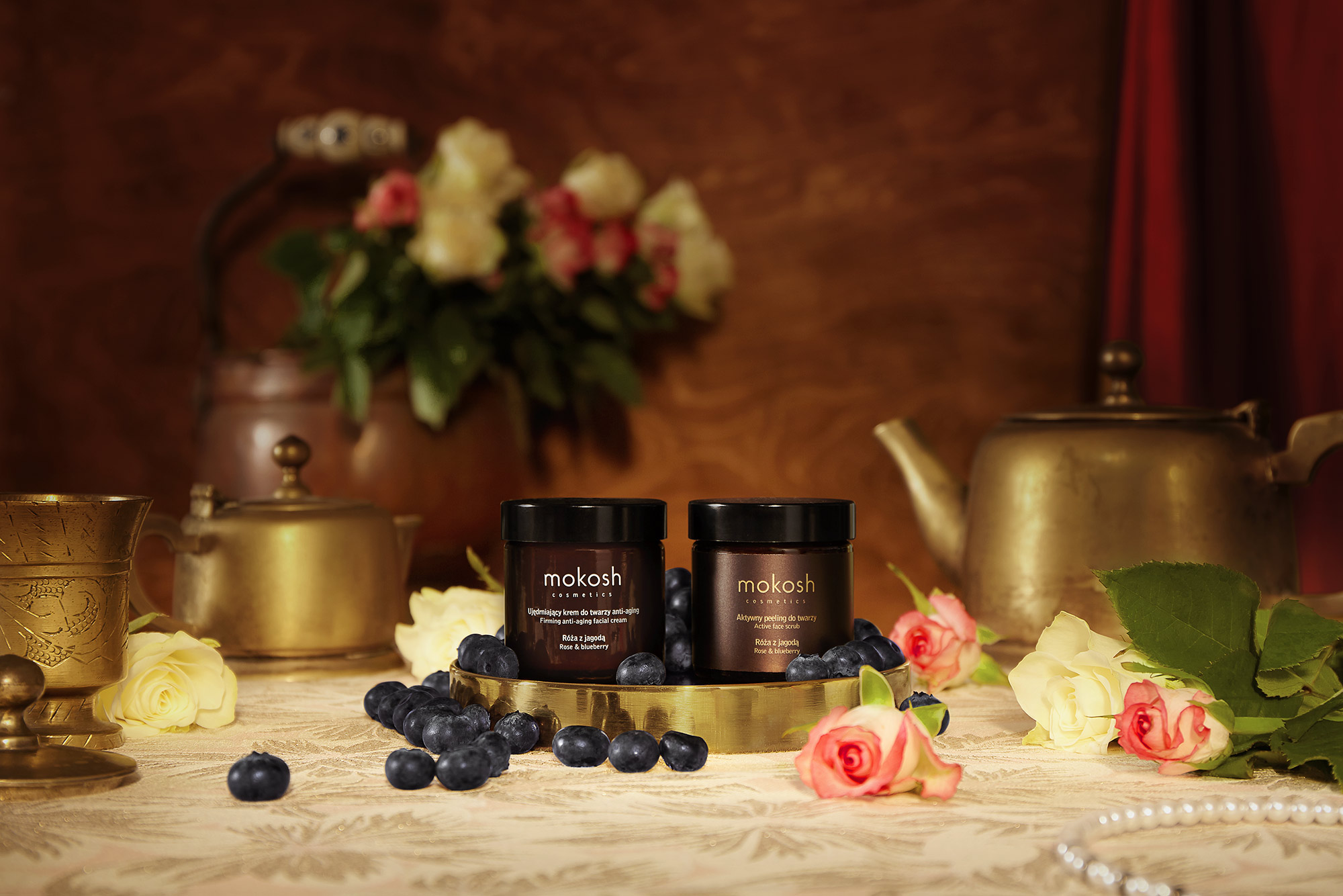 cosmetics laid in a set stylized as a baroque room with roses, berries, copper cutlery in a consistent colour mood